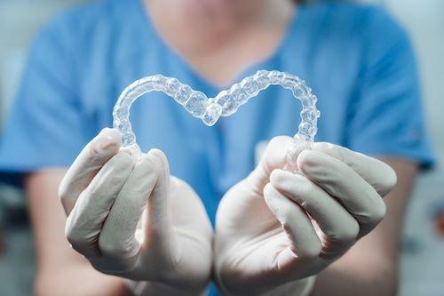 dental professional holding invisalign aligners in the shape of a heart