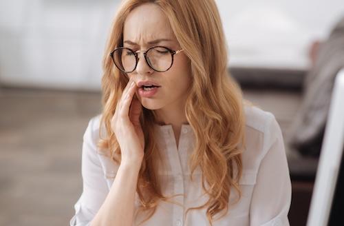 woman holding jaw from dental emergency
