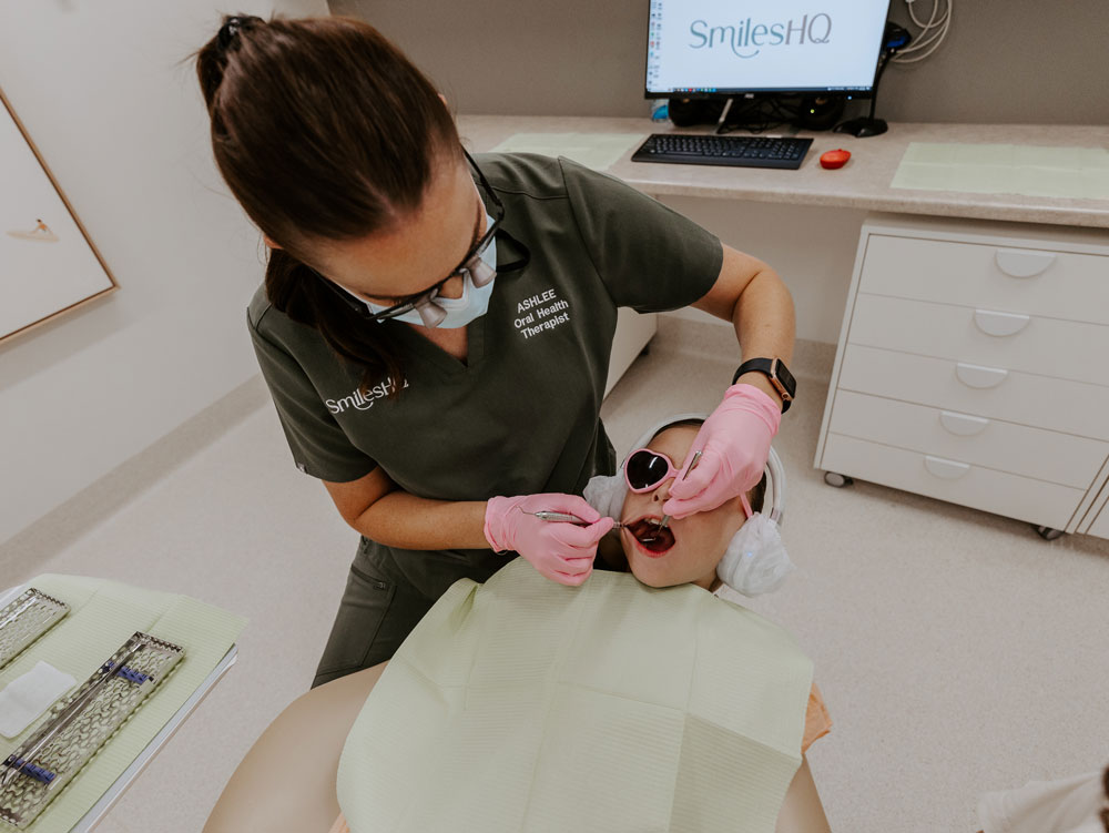Oral health therapist Ashlee cleaning a young patient's teeth