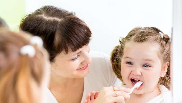 warners bay mom helping young daughter brush her teeth