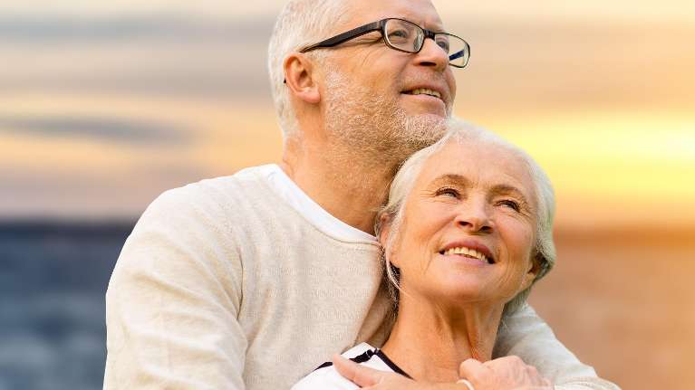older man and woman hugging on the beach