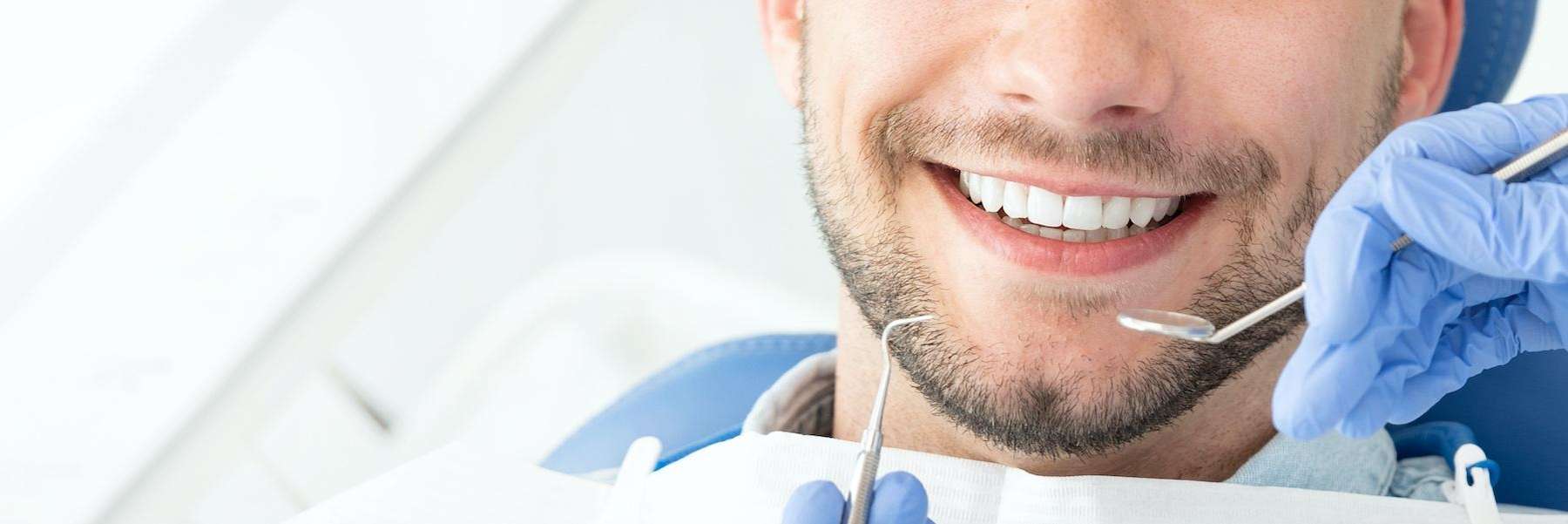 warners bay man smiling with dental tools near his mouth
