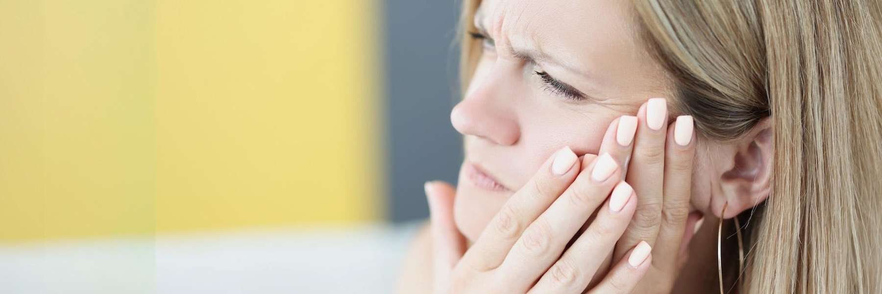 woman holding jaw from tooth pain during a dental emergency